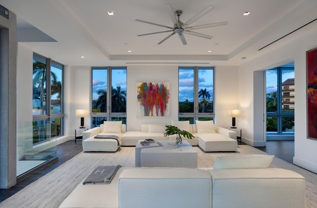 living room with floor to ceiling windows, dark hardwood / wood-style floors, ceiling fan, and a tray ceiling