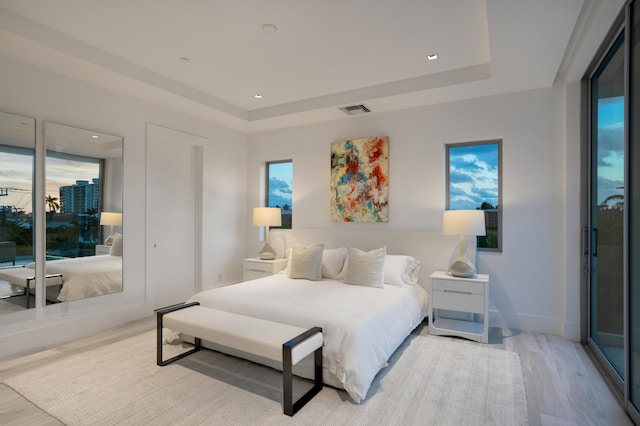 bedroom with a raised ceiling and light hardwood / wood-style floors