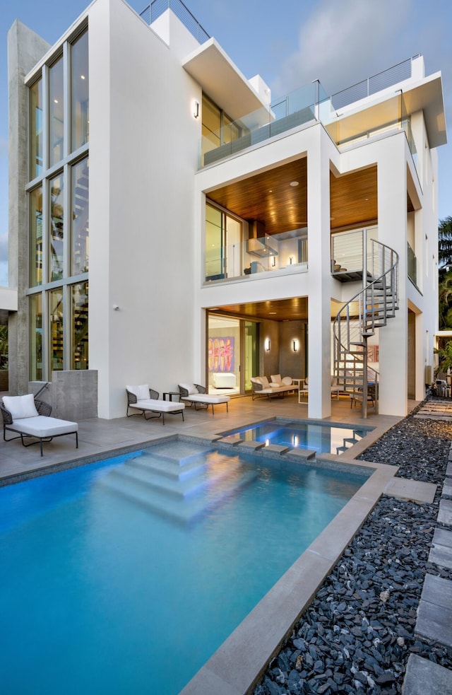 rear view of property featuring a patio and a pool with hot tub