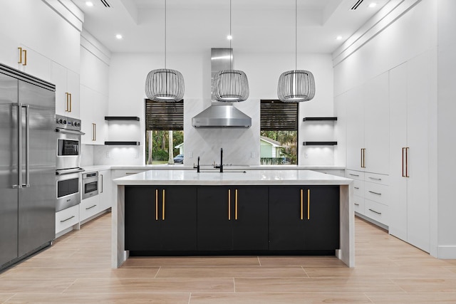 kitchen with a kitchen island with sink, white cabinets, pendant lighting, and appliances with stainless steel finishes