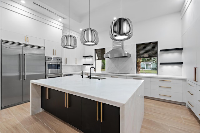 kitchen with a center island with sink, decorative light fixtures, white cabinetry, and stainless steel built in refrigerator