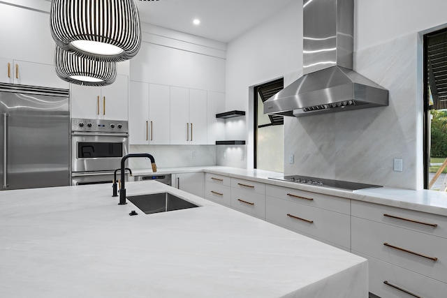 kitchen featuring white cabinetry, sink, stainless steel appliances, wall chimney range hood, and decorative backsplash