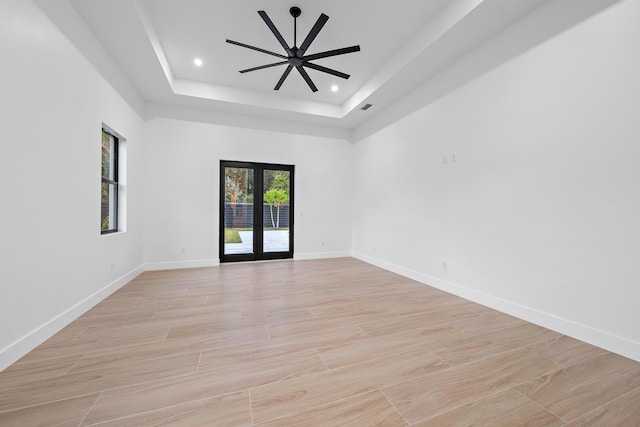 spare room with french doors, light wood-type flooring, a raised ceiling, and ceiling fan