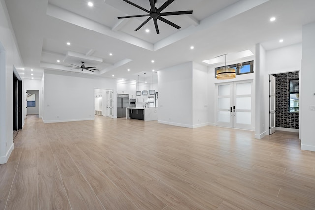 unfurnished living room with ceiling fan, french doors, light hardwood / wood-style floors, and coffered ceiling