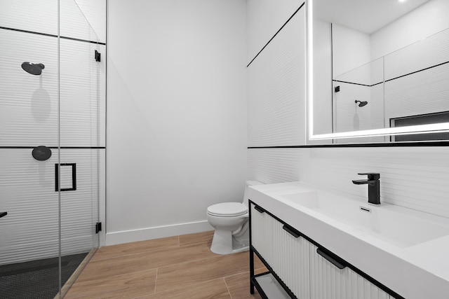 bathroom featuring hardwood / wood-style floors, vanity, toilet, and an enclosed shower