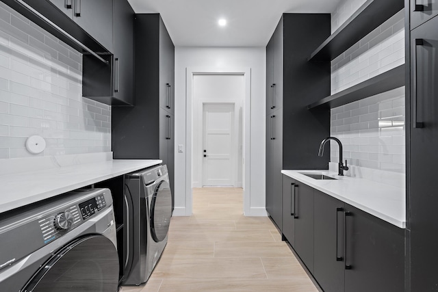 washroom with cabinets, washing machine and dryer, and sink