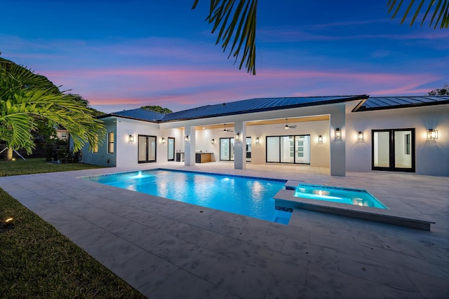 pool at dusk featuring an in ground hot tub, french doors, ceiling fan, and a patio area