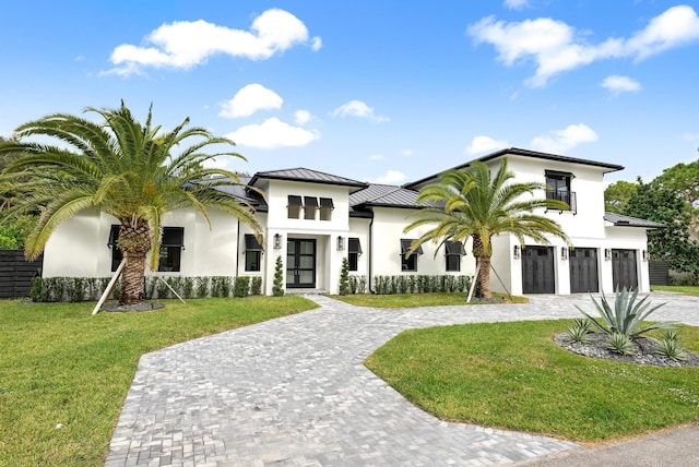 view of front facade featuring a front yard, french doors, a balcony, and a garage