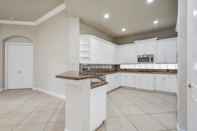 kitchen featuring sink, light tile patterned floors, dark stone countertops, white cabinets, and kitchen peninsula