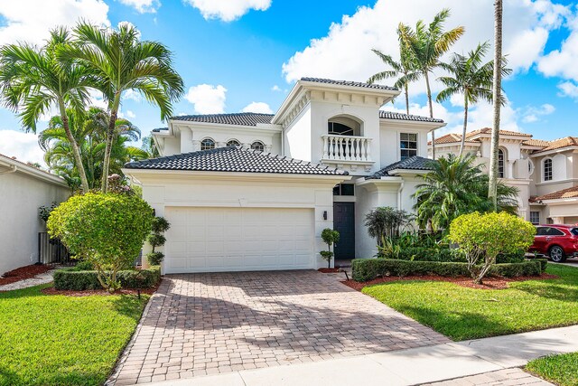 mediterranean / spanish-style home with a balcony, a garage, and a front yard