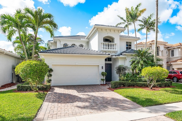 mediterranean / spanish house with a garage, a front lawn, and a balcony