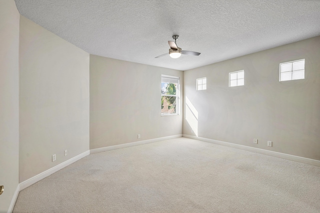 empty room featuring ceiling fan, light carpet, and a textured ceiling