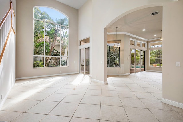 interior space featuring light tile patterned floors, crown molding, and a high ceiling