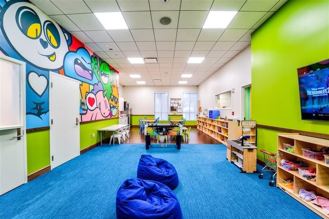 recreation room featuring carpet flooring and a drop ceiling