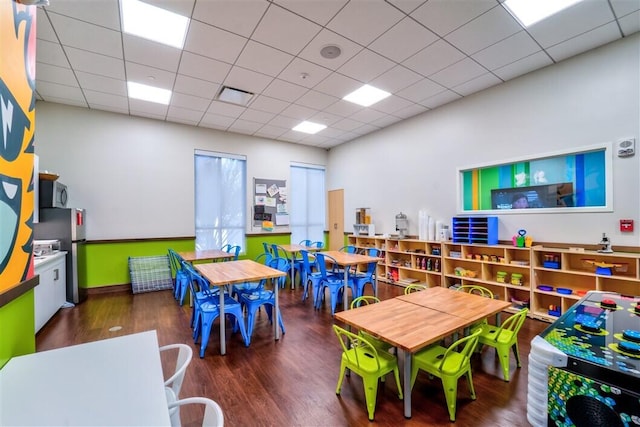 playroom featuring dark wood-type flooring and a paneled ceiling