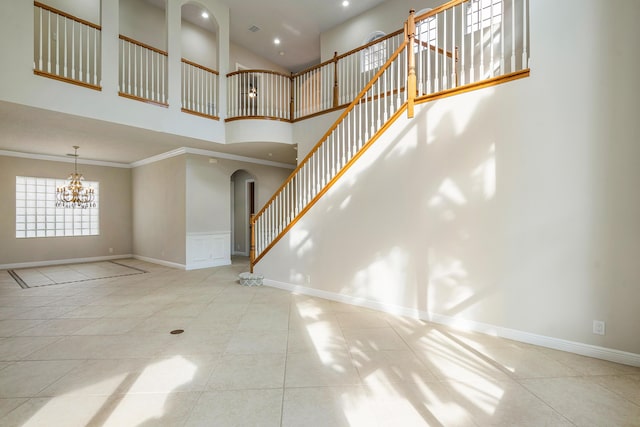 interior space featuring a high ceiling, ornamental molding, light tile patterned flooring, and a notable chandelier