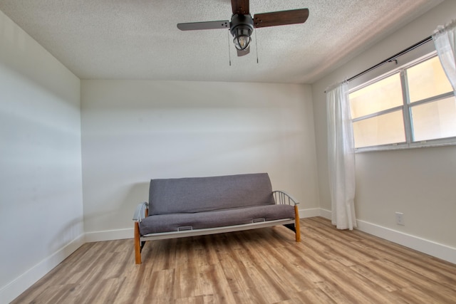 living area with a textured ceiling, ceiling fan, and light hardwood / wood-style floors