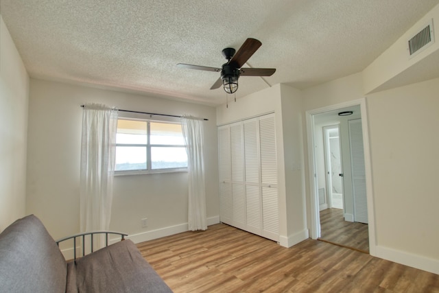 unfurnished room featuring ceiling fan, light wood-type flooring, and a textured ceiling