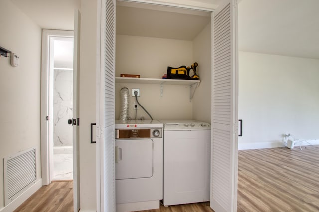 laundry room featuring independent washer and dryer and light hardwood / wood-style floors