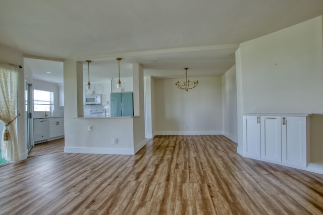 unfurnished living room featuring light wood-type flooring, sink, and an inviting chandelier