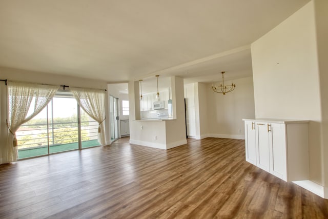 unfurnished living room with wood-type flooring and a chandelier