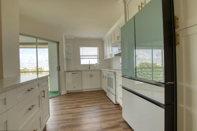 kitchen with stove, wood-type flooring, tasteful backsplash, white cabinetry, and dishwashing machine