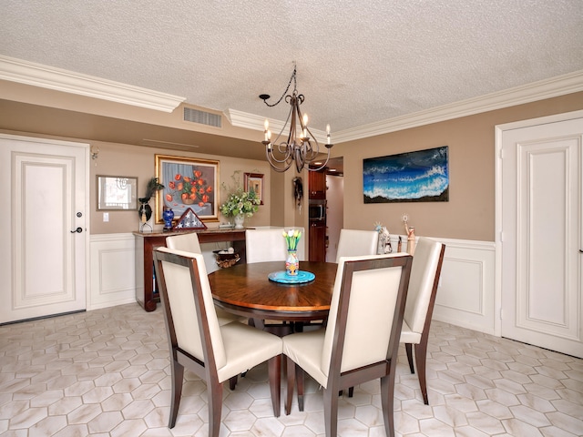 tiled dining room featuring a textured ceiling, crown molding, and an inviting chandelier