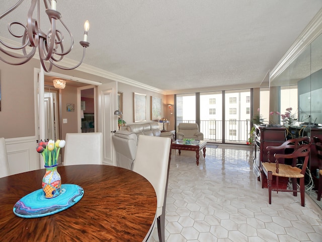 dining room with light tile patterned flooring, a textured ceiling, ornamental molding, and an inviting chandelier