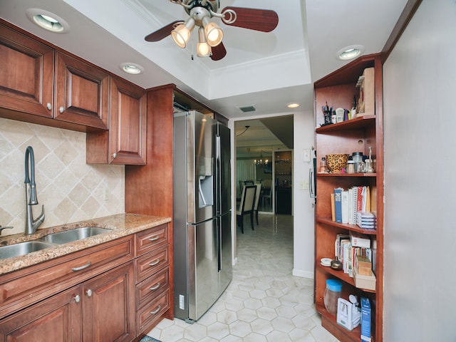 kitchen featuring ceiling fan, a tray ceiling, sink, stainless steel fridge, and backsplash