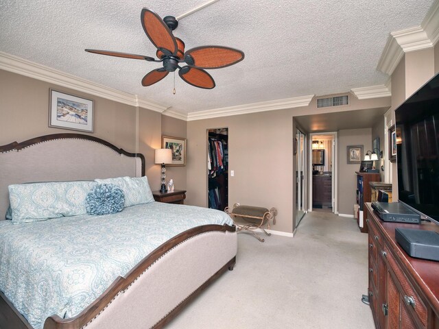 carpeted bedroom featuring crown molding, a walk in closet, a textured ceiling, and a closet