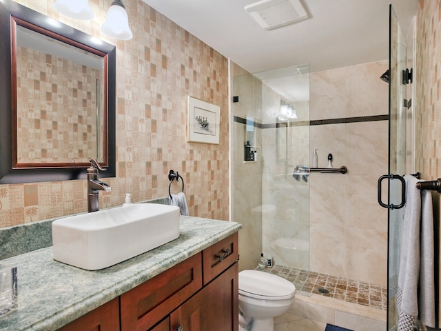 bathroom featuring vanity, tile patterned floors, tile walls, toilet, and a shower with door