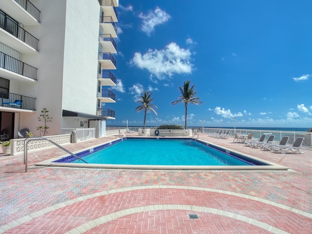 view of swimming pool featuring a water view and a patio