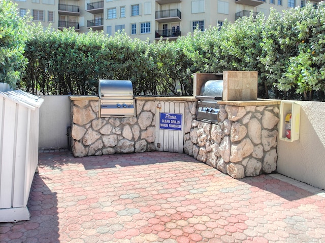 view of patio featuring a balcony, area for grilling, and exterior kitchen