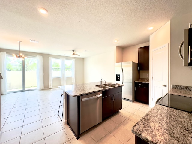 kitchen featuring dark brown cabinets, light tile patterned floors, ceiling fan, appliances with stainless steel finishes, and a center island with sink