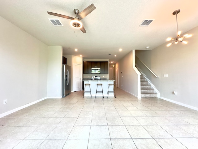 kitchen featuring a kitchen island with sink, stainless steel appliances, light tile patterned floors, and a breakfast bar