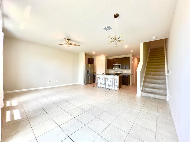 unfurnished living room with ceiling fan with notable chandelier and light tile patterned floors