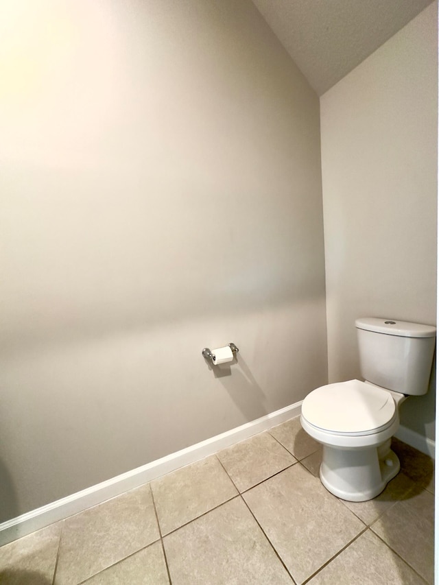 bathroom featuring toilet, a textured ceiling, tile patterned flooring, and vaulted ceiling