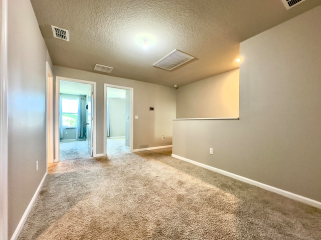 empty room with carpet flooring and a textured ceiling