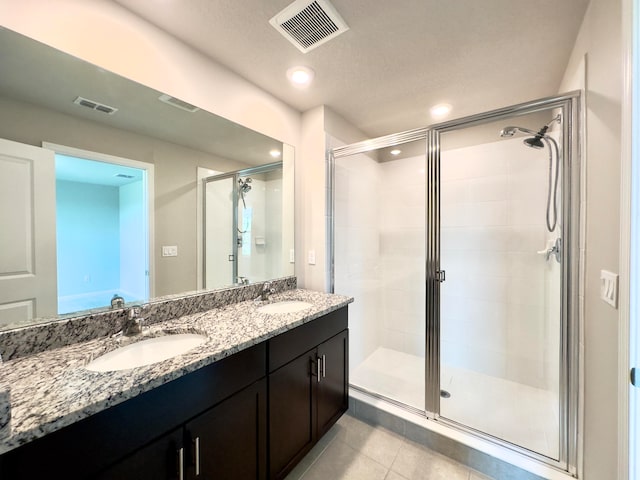 bathroom with a shower with shower door, tile patterned floors, a textured ceiling, and double vanity