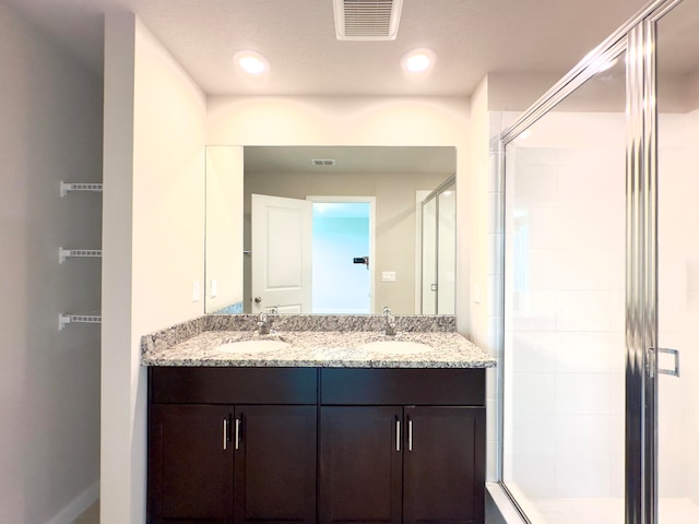 bathroom with dual vanity and an enclosed shower