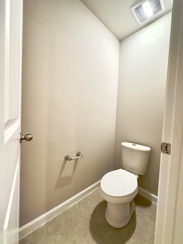 bathroom with toilet, a textured ceiling, and tile patterned flooring