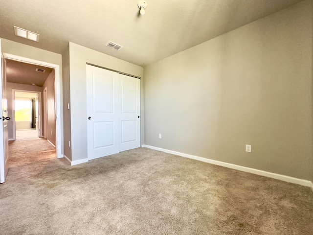 unfurnished bedroom with a closet and light colored carpet