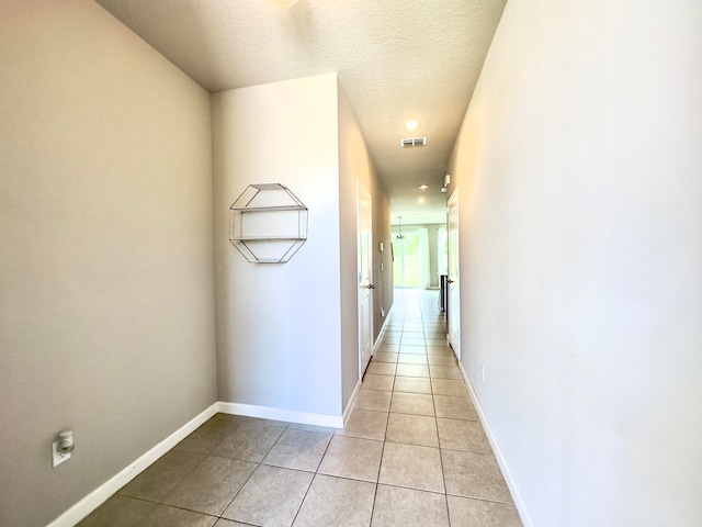 corridor with light tile patterned flooring and a textured ceiling