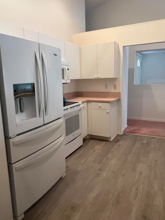 kitchen with white cabinets, light wood-type flooring, and white appliances