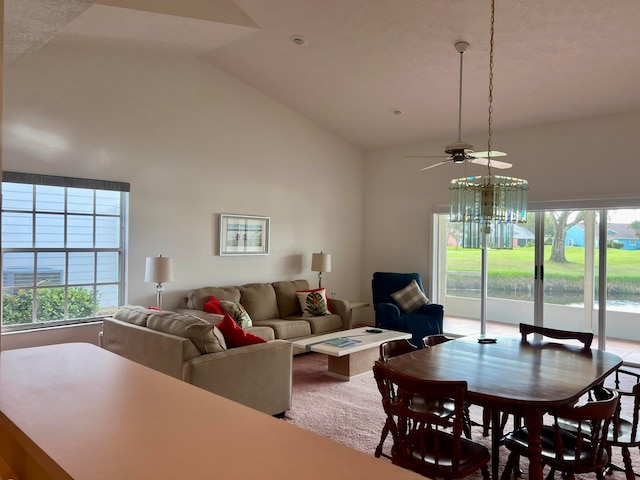 dining space featuring high vaulted ceiling, ceiling fan with notable chandelier, and plenty of natural light