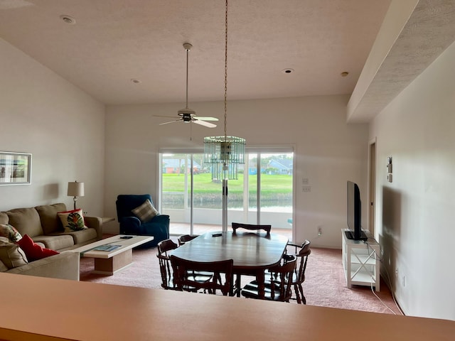 carpeted dining room with a towering ceiling and ceiling fan with notable chandelier