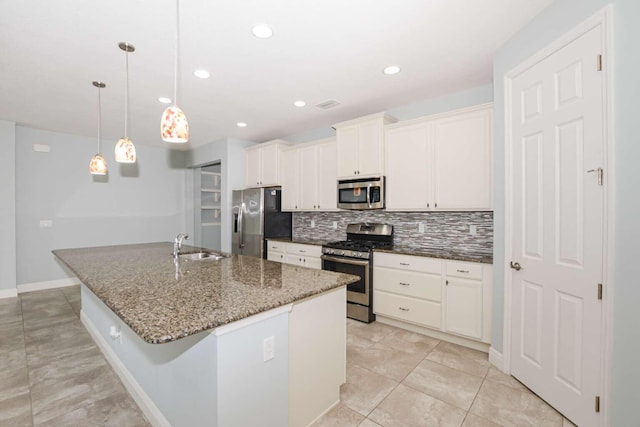 kitchen featuring a kitchen island with sink, stainless steel appliances, a sink, white cabinetry, and backsplash