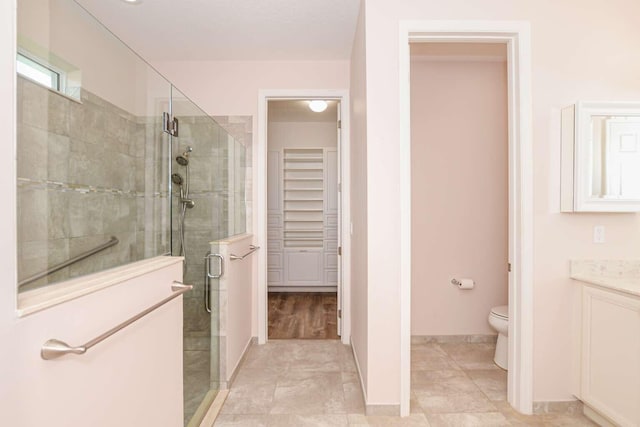 bathroom with vanity, toilet, hardwood / wood-style flooring, and walk in shower