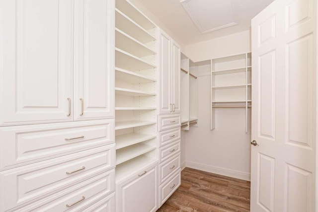 walk in closet with dark wood-style floors and attic access