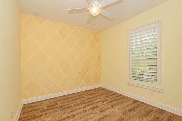 spare room featuring a ceiling fan, baseboards, and wood finished floors